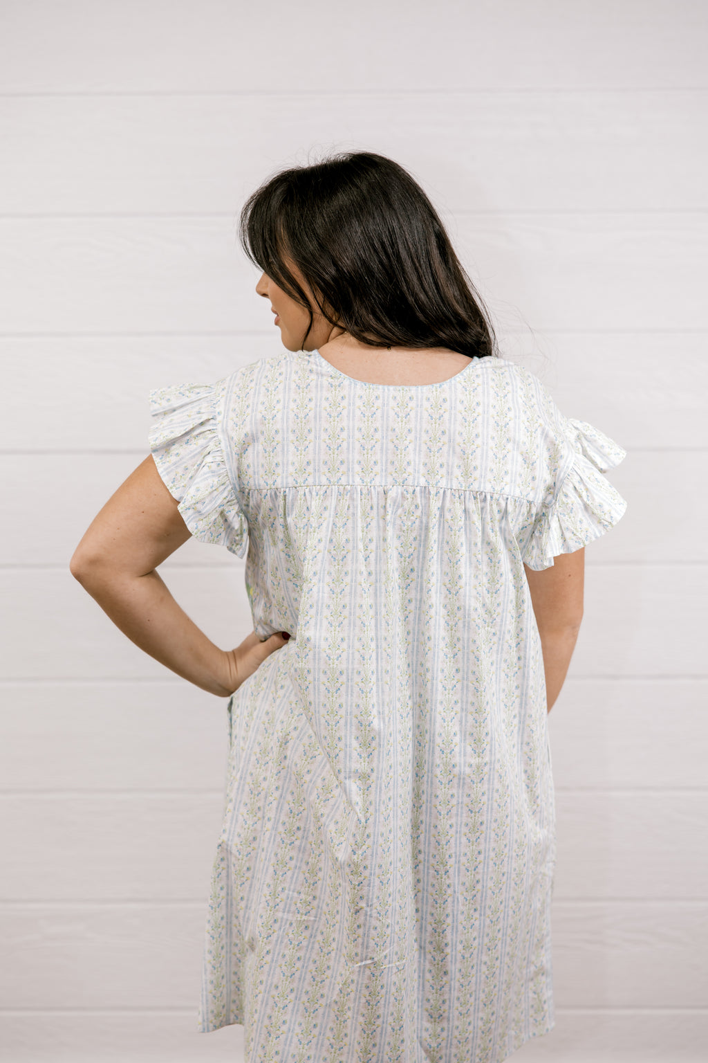 Woman wearing a white dress with ruffled sleeves against a light background