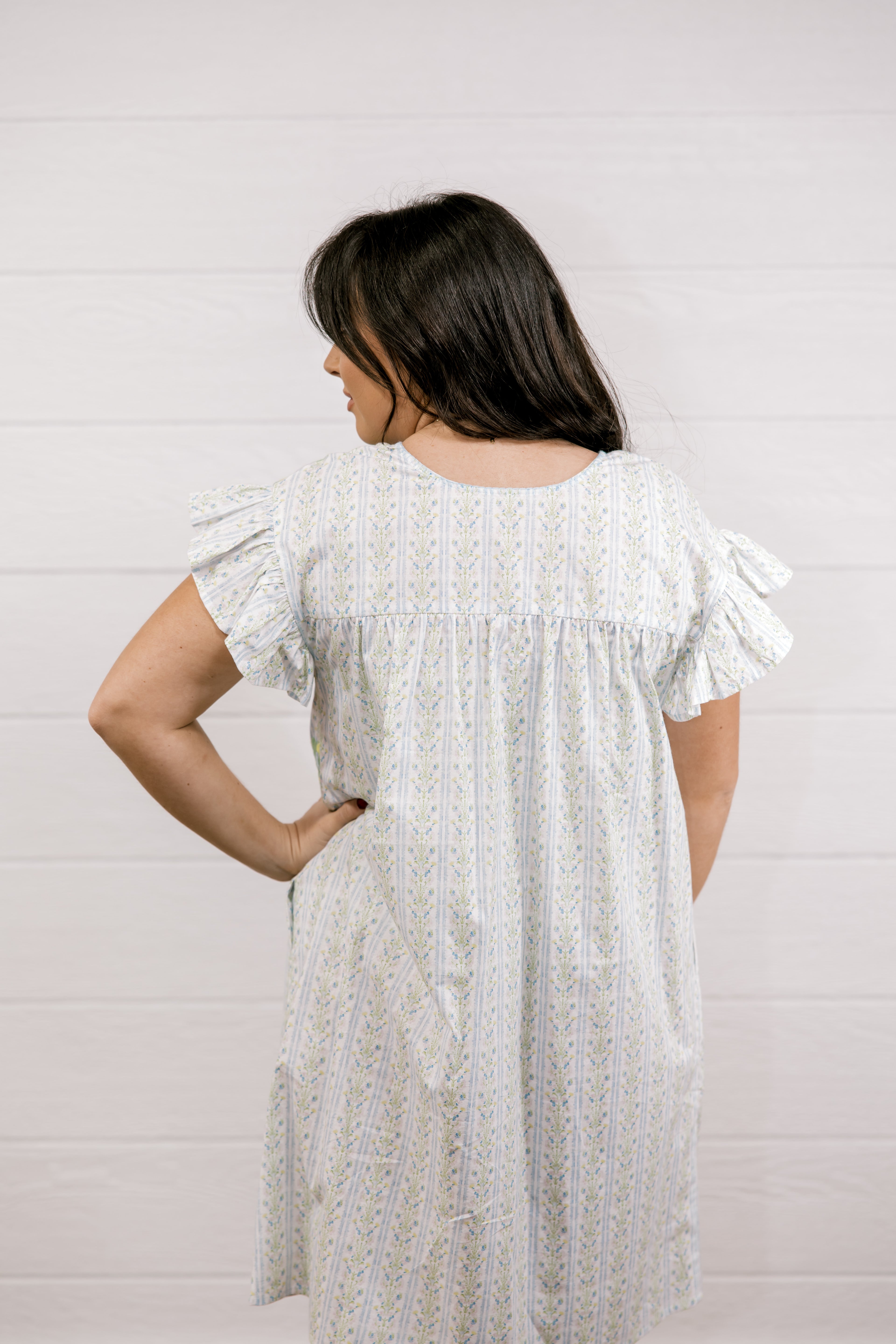 Woman wearing a white dress with ruffled sleeves against a light background