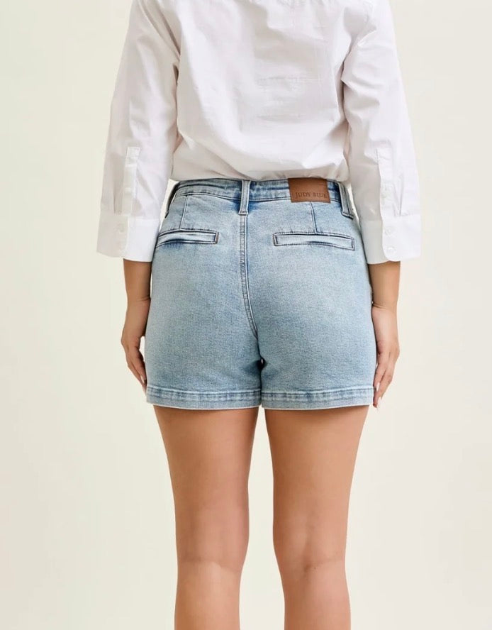 Person wearing light blue denim shorts and a white shirt on a plain background