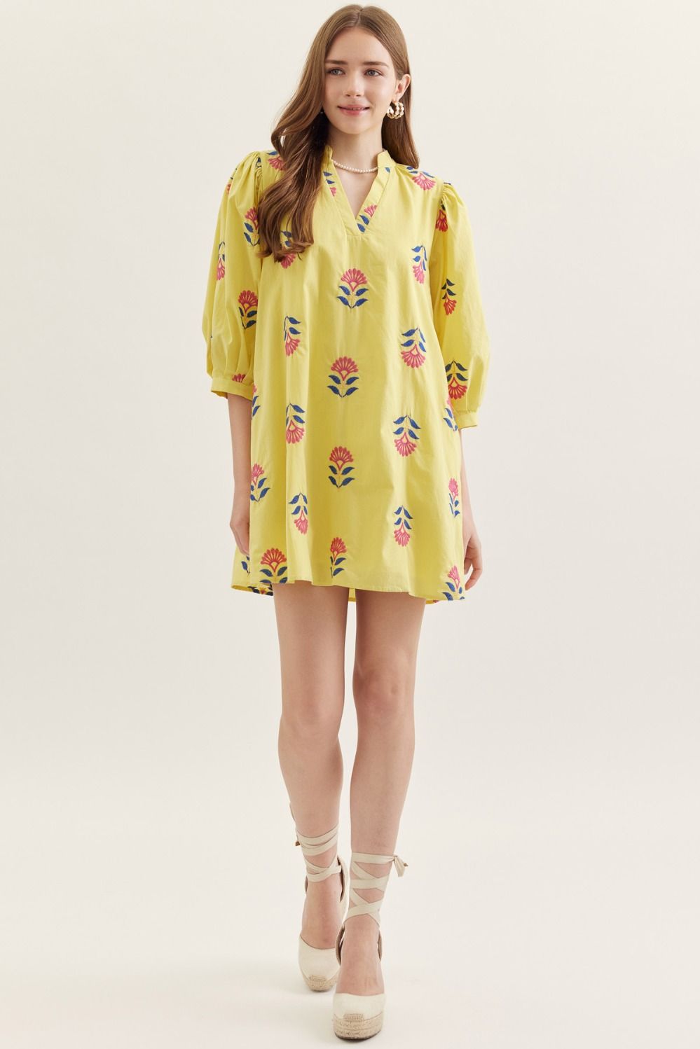Woman wearing a yellow floral dress on a white background