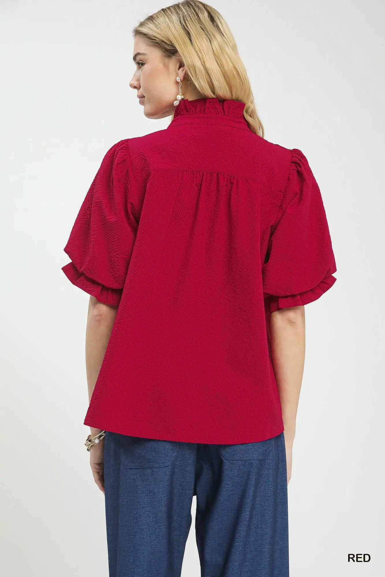 Red blouse with ruffled sleeves worn by a person on a white background