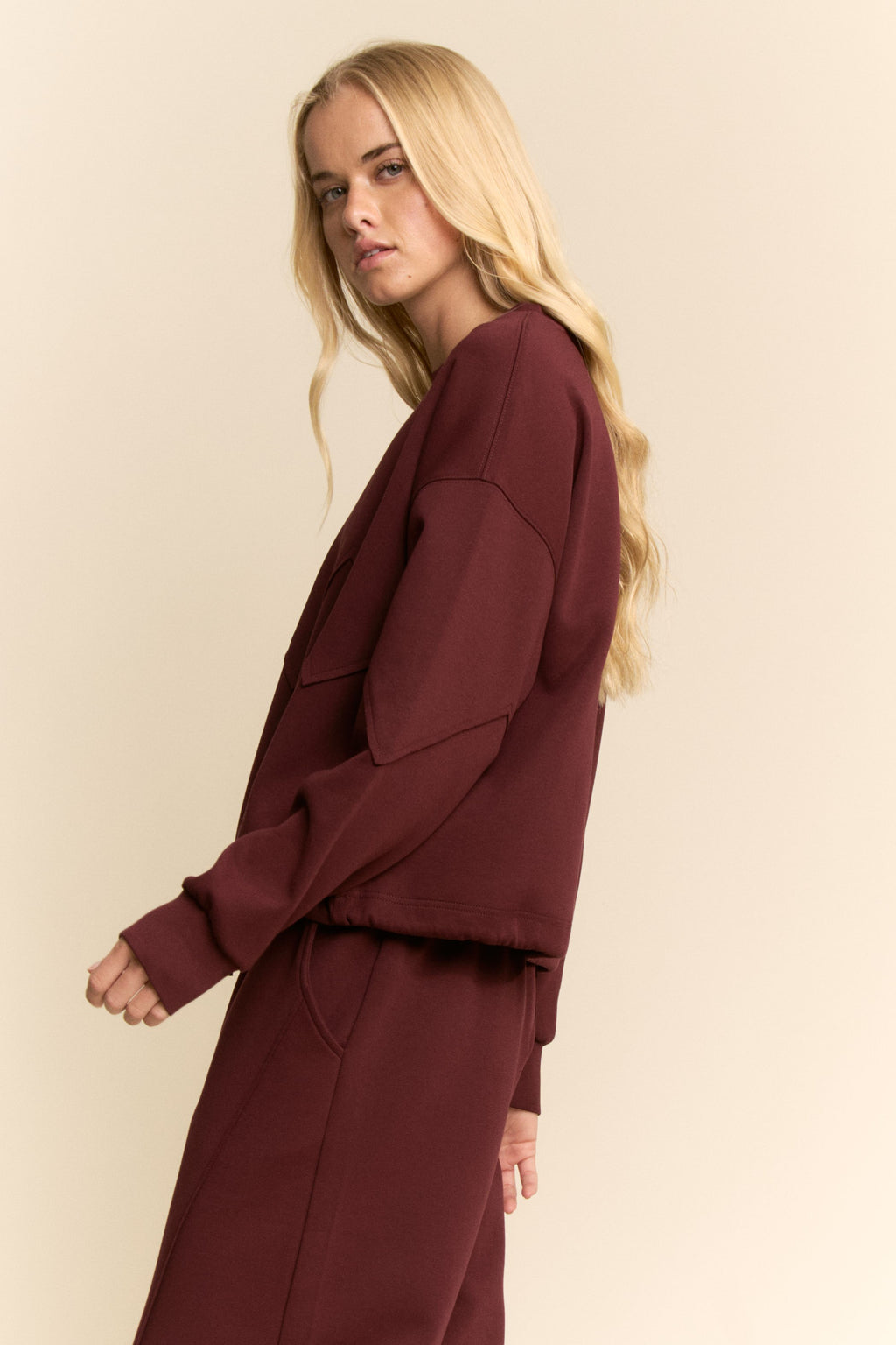 Woman wearing a burgundy outfit against a beige background