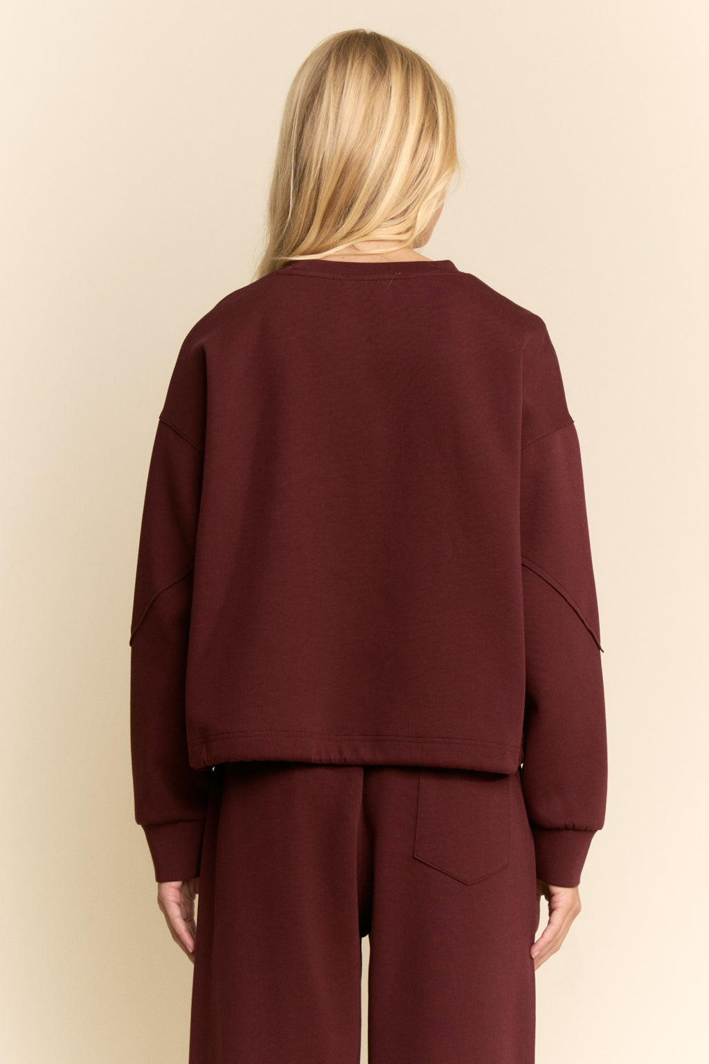 Maroon outfit worn by a person on a beige background