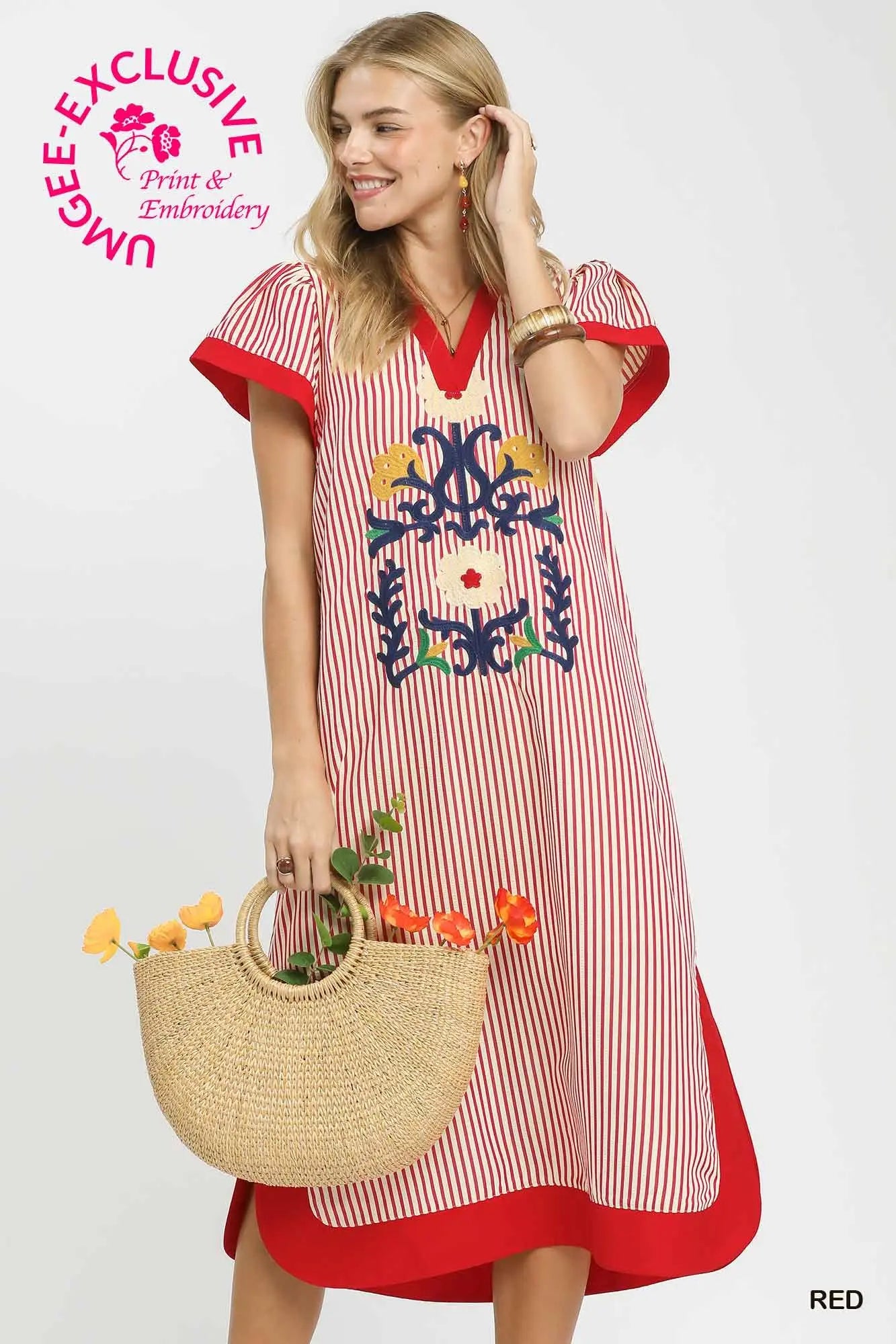 Woman wearing a red and white striped dress with embroidery, holding a straw bag with flowers, on a white background.