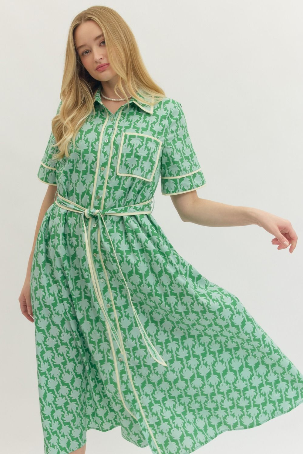 Woman wearing a green patterned dress with a white background