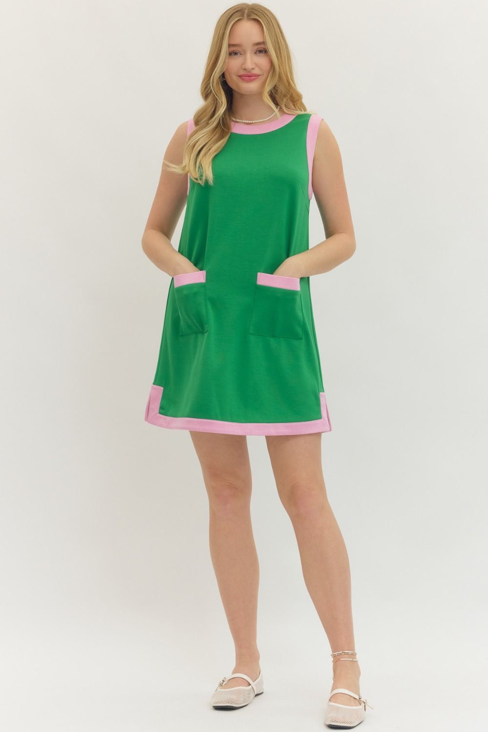 Woman wearing a green dress with pink trim on a white background