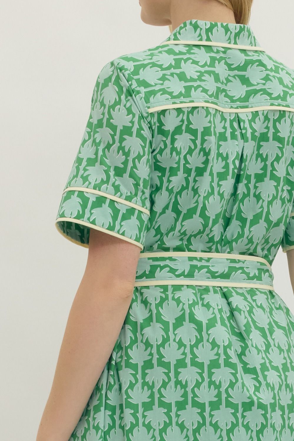 Green patterned dress with white trim on a plain background