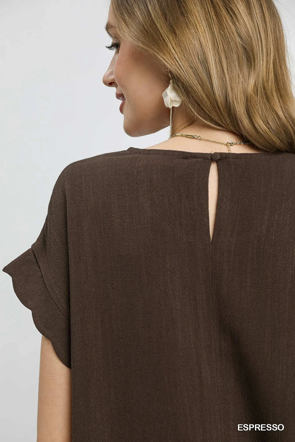 Woman wearing an espresso-colored top with a plain background