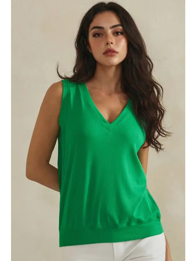 Woman wearing a green sleeveless top against a beige background