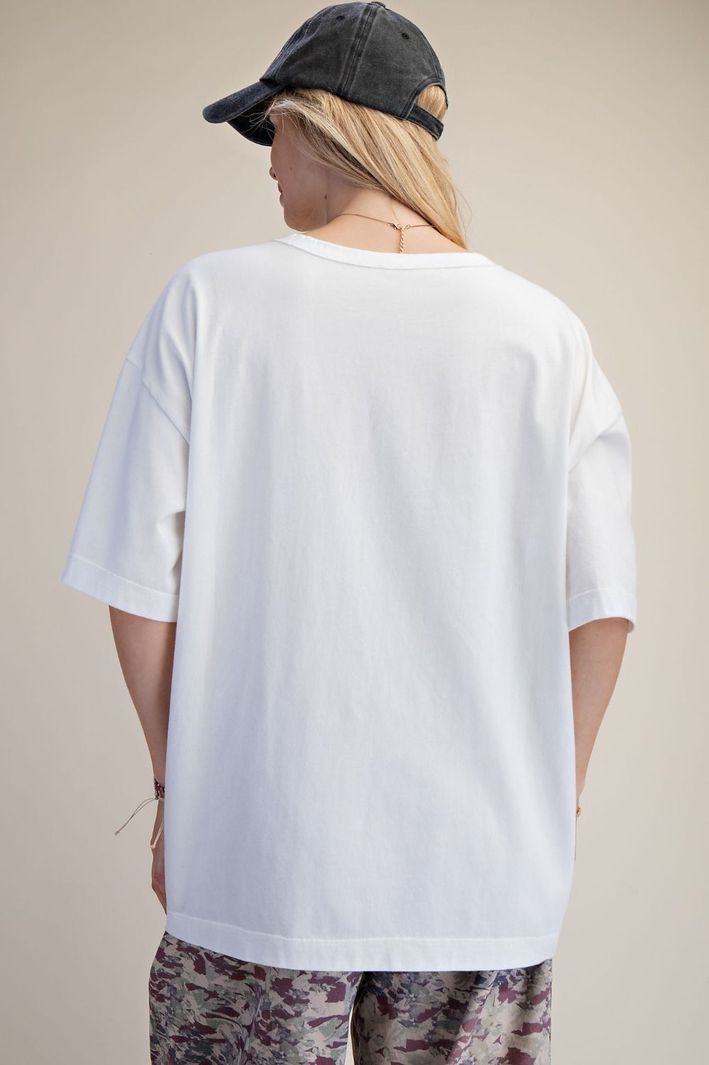 Person wearing a plain white t-shirt and camouflage pants on a beige background