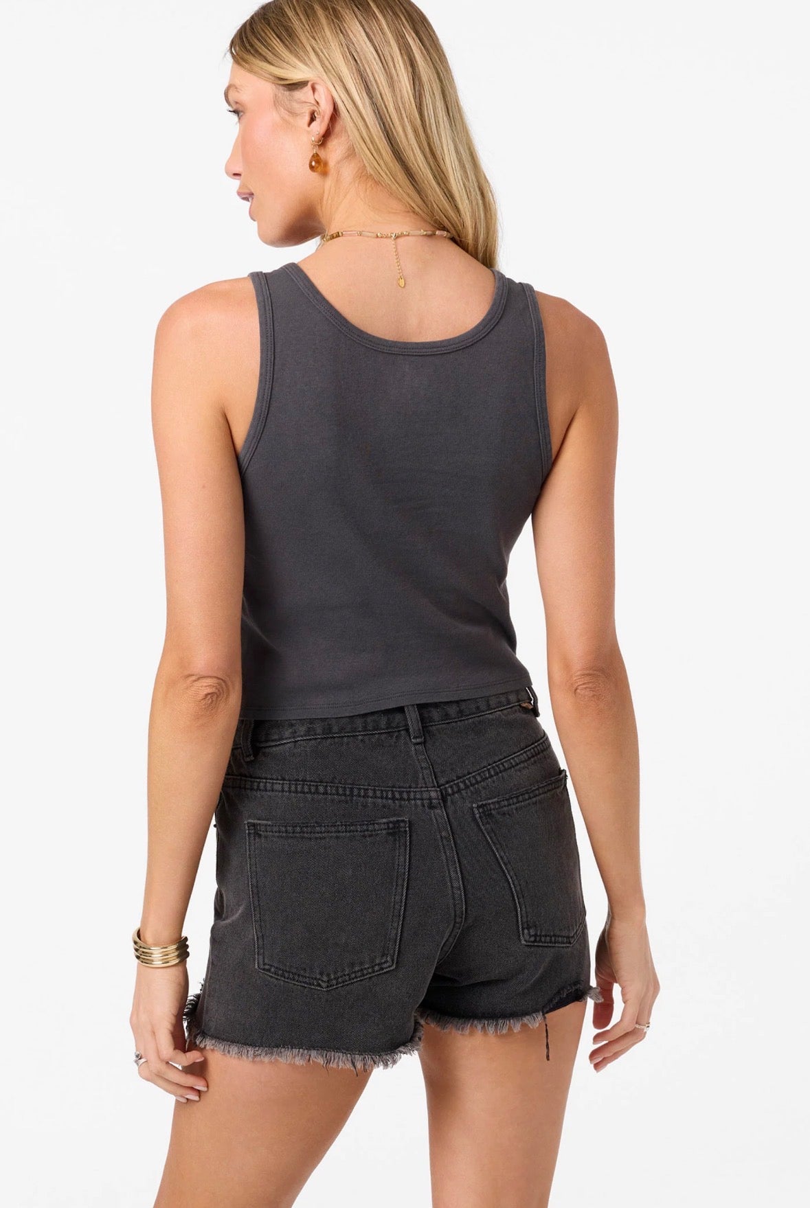 Woman wearing a black tank top and denim shorts on a white background