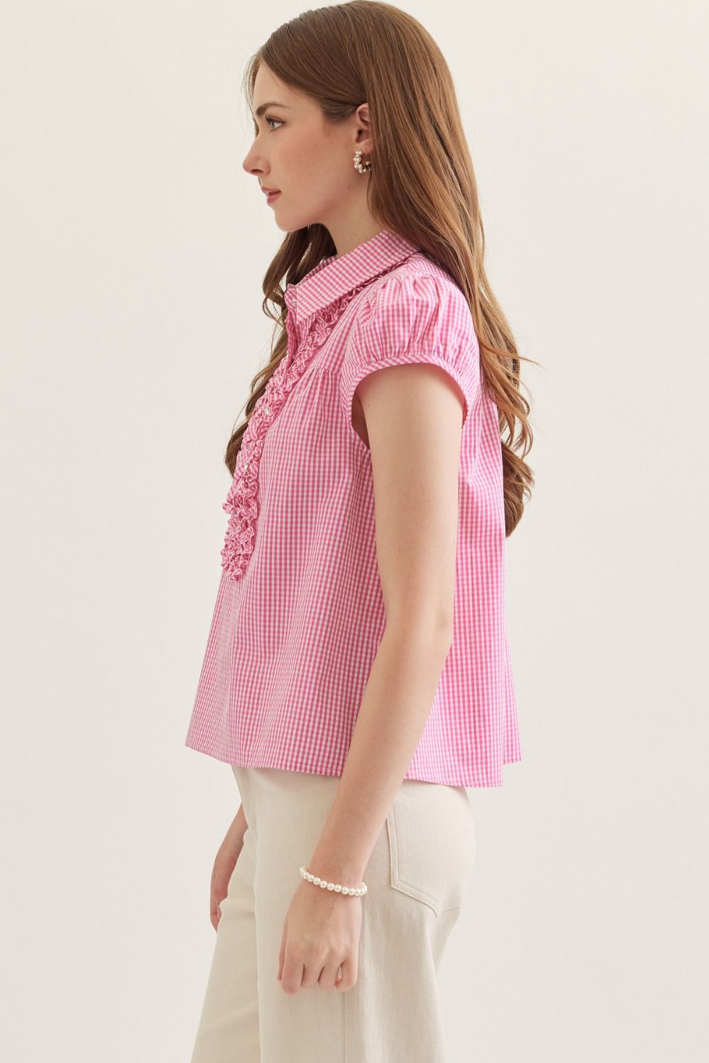 Woman wearing a pink checkered blouse with a white background