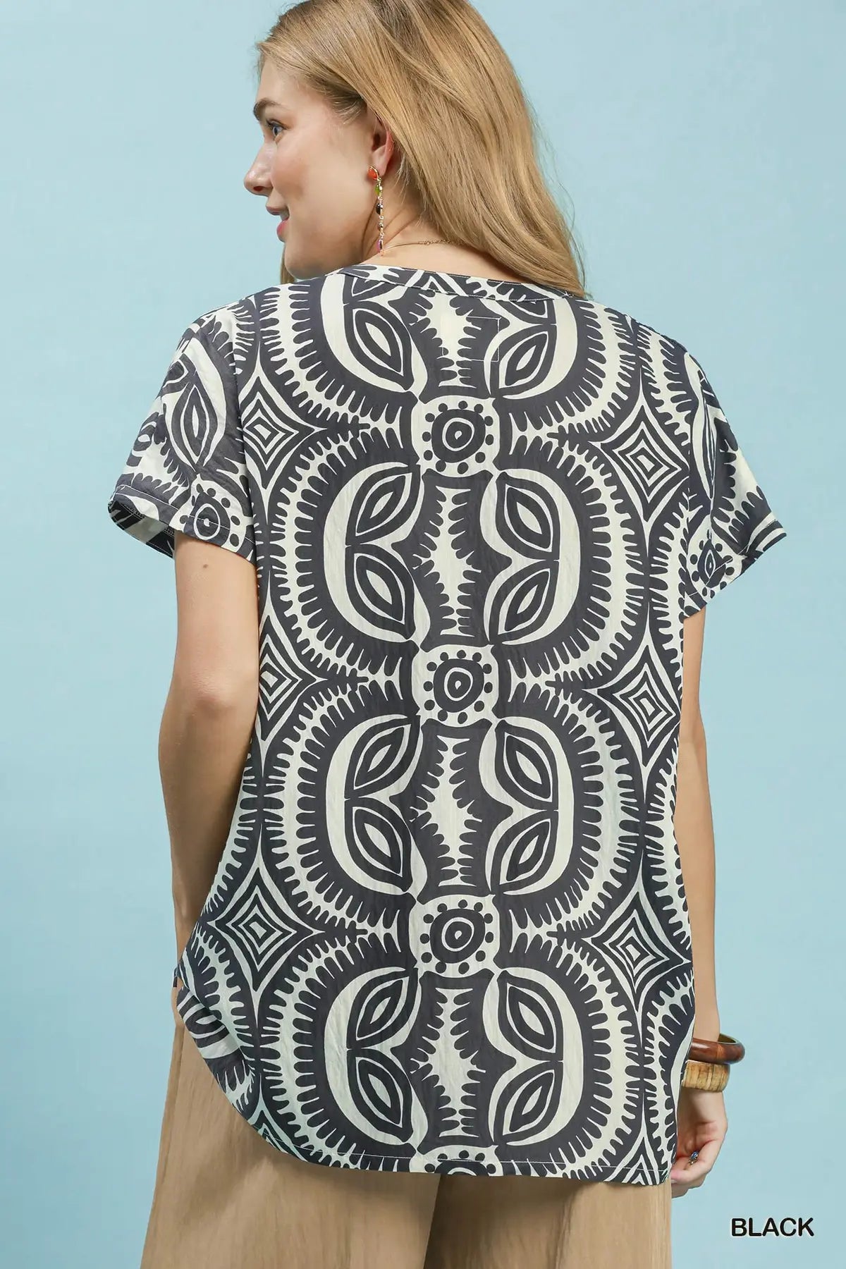 Woman wearing a black and white patterned shirt against a light blue background