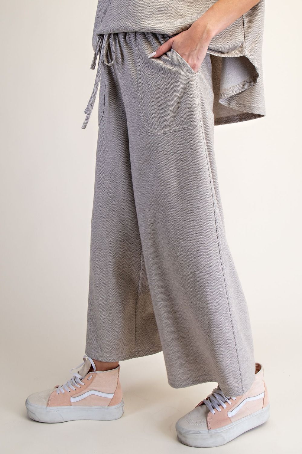 Person wearing gray wide-leg pants with a neutral background