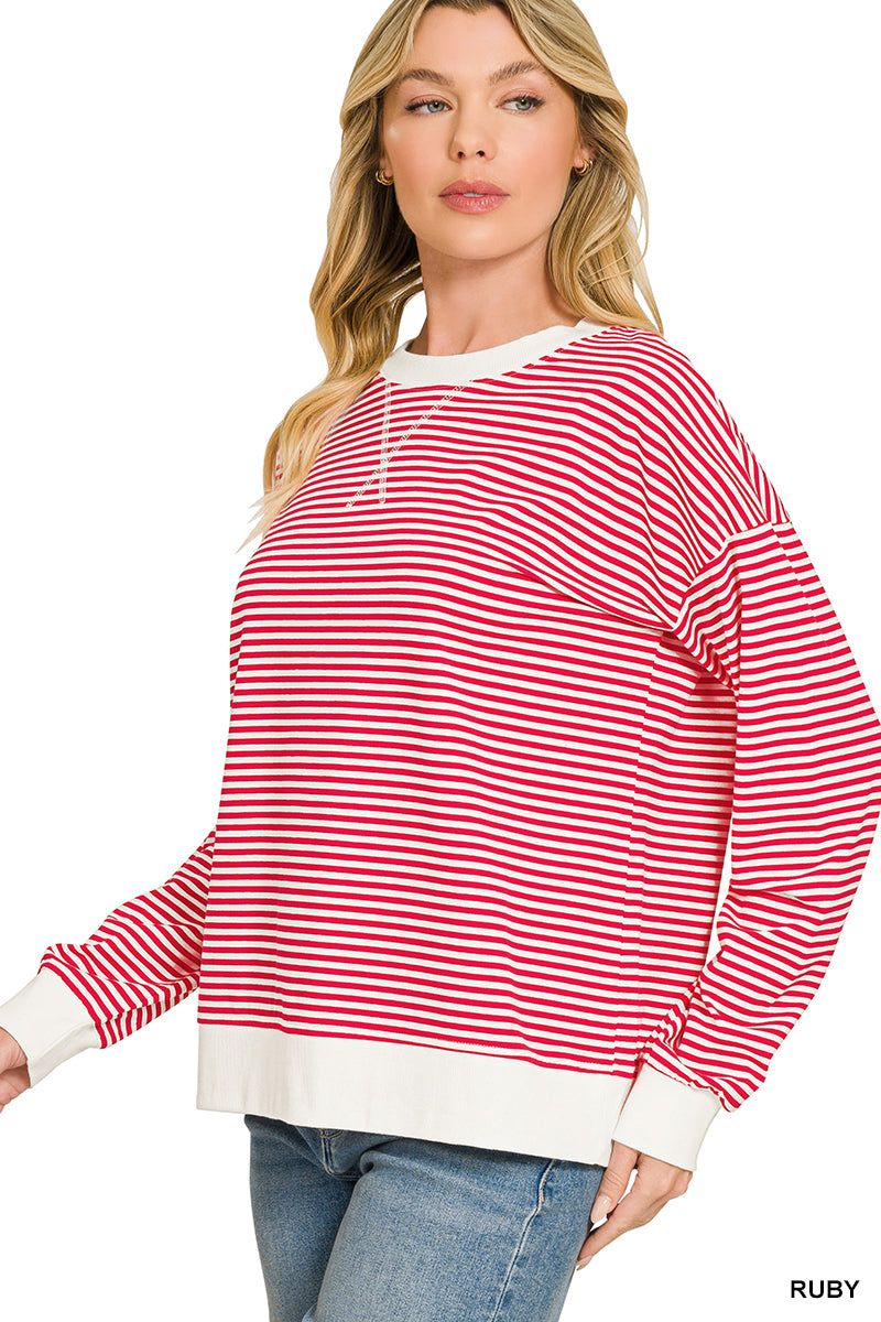 A woman wearing a red and white horizontally striped long-sleeve sweatshirt with solid white ribbed trim at the crew neck, cuffs, and hem, paired with blue jeans against a plain white background.