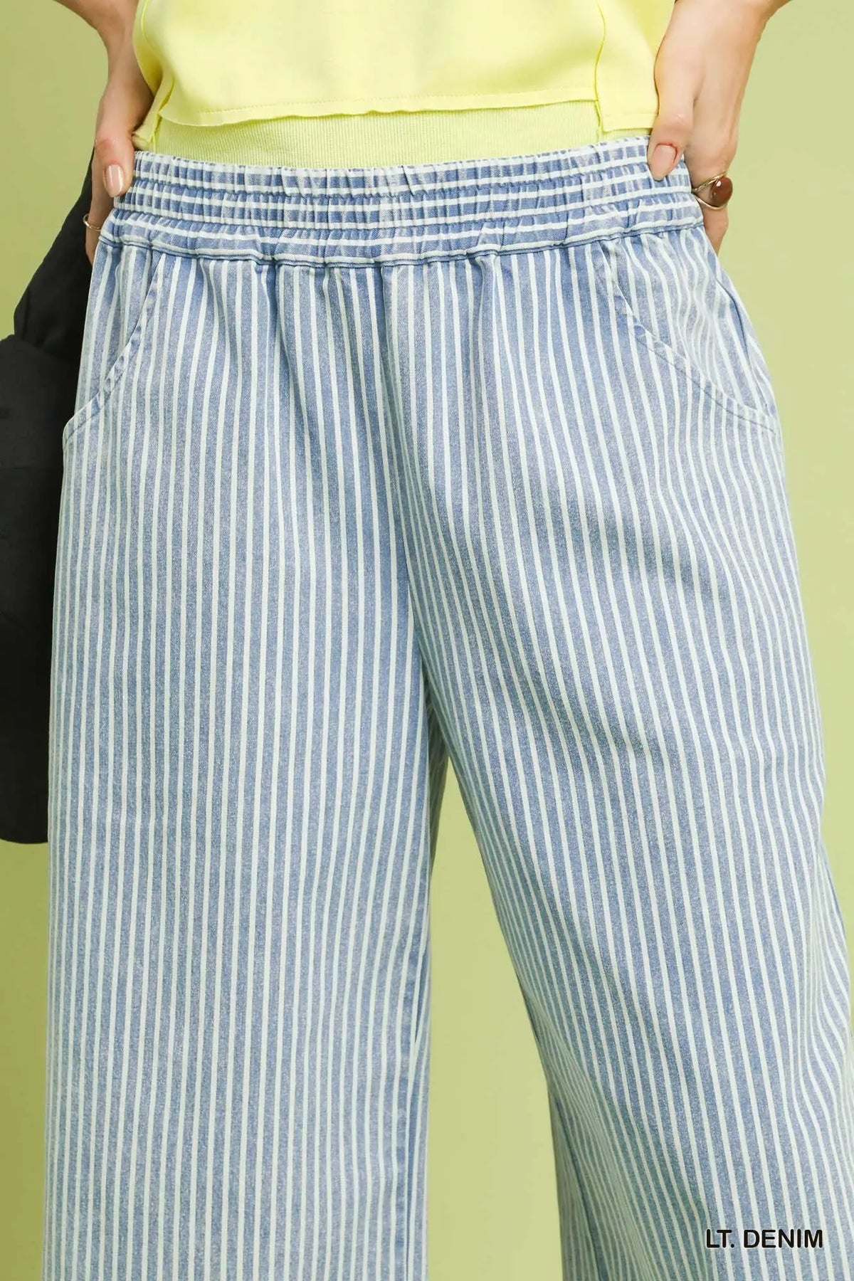 Light blue and white striped pants worn by a person against a green background