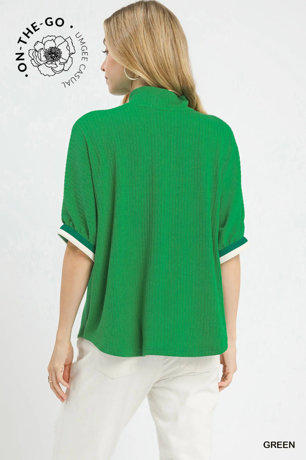 Woman wearing a green blouse with white trim on a white background