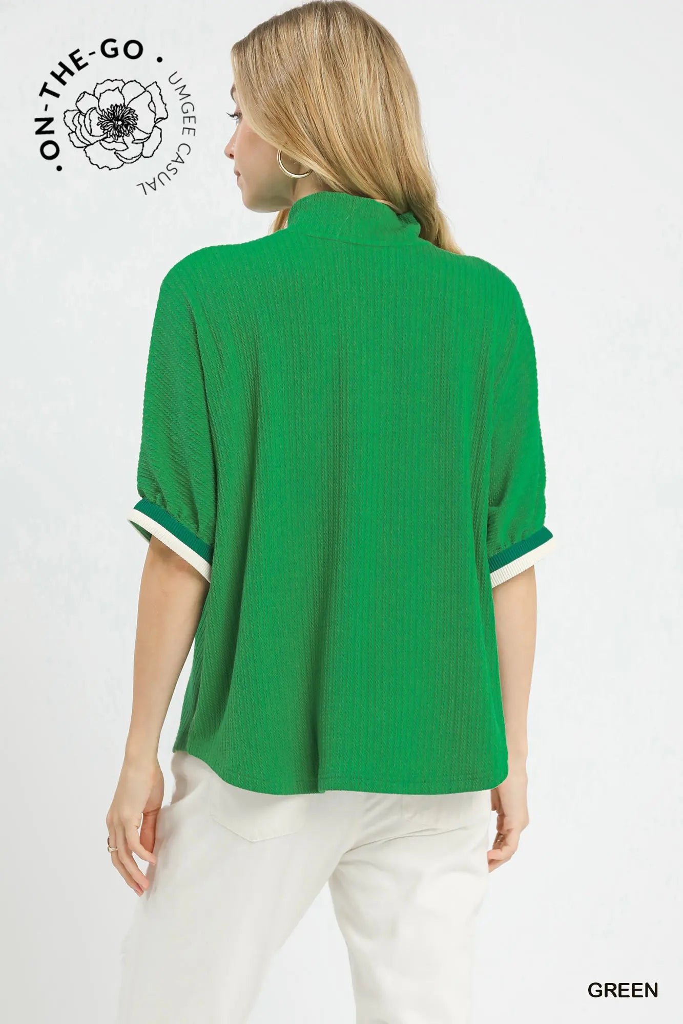 Woman wearing a green blouse with white trim on a white background