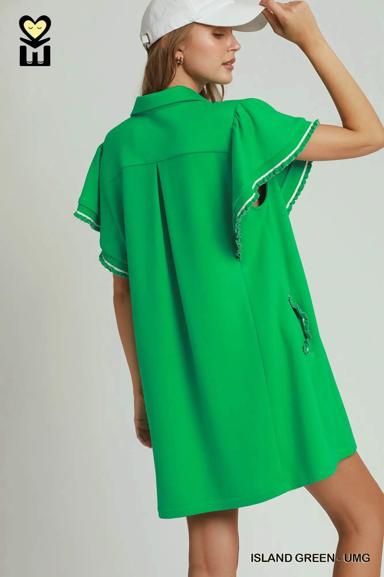 Woman wearing a green dress with white trim on a plain background
