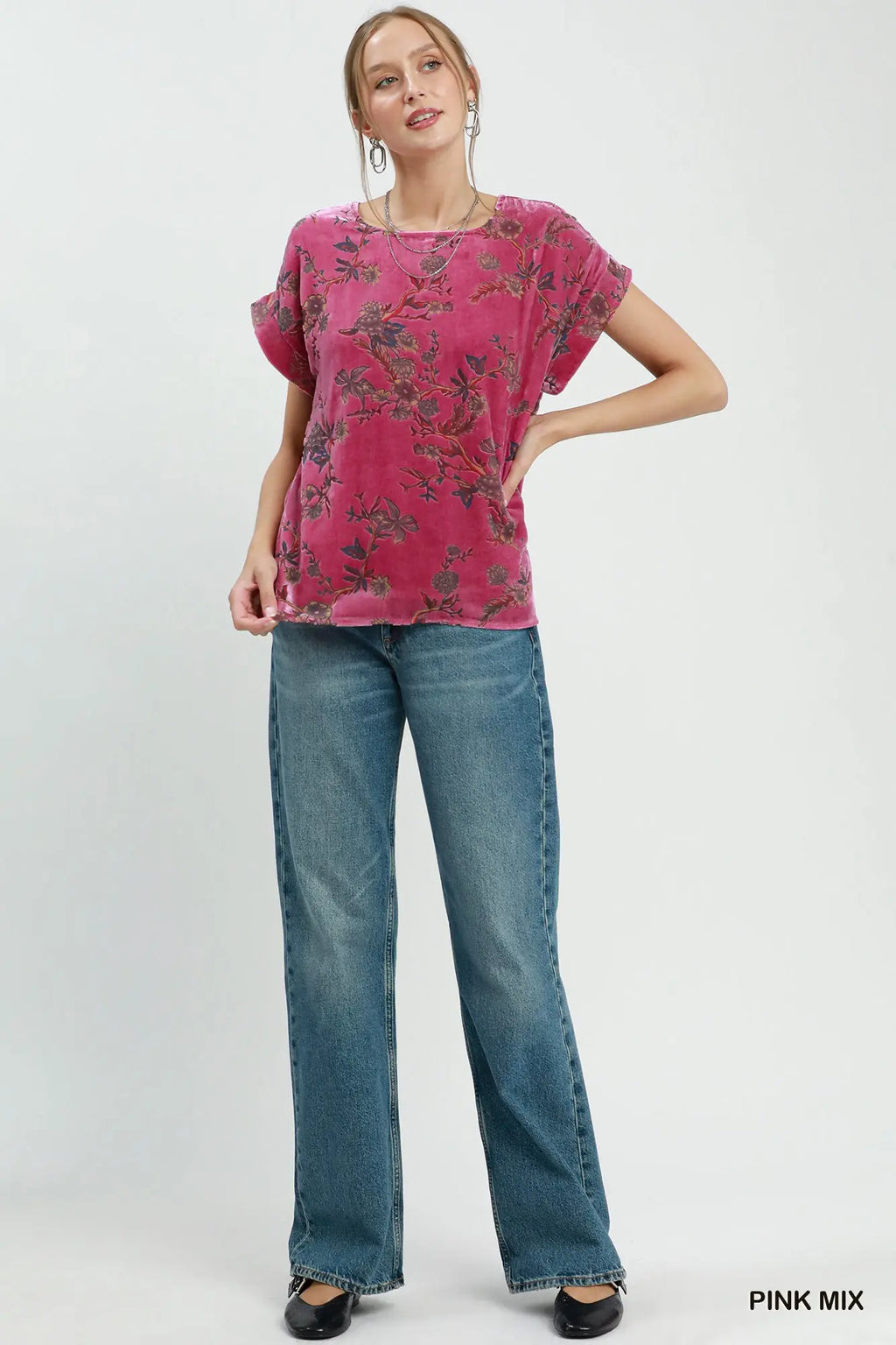 Woman wearing a pink floral top and blue jeans on a white background