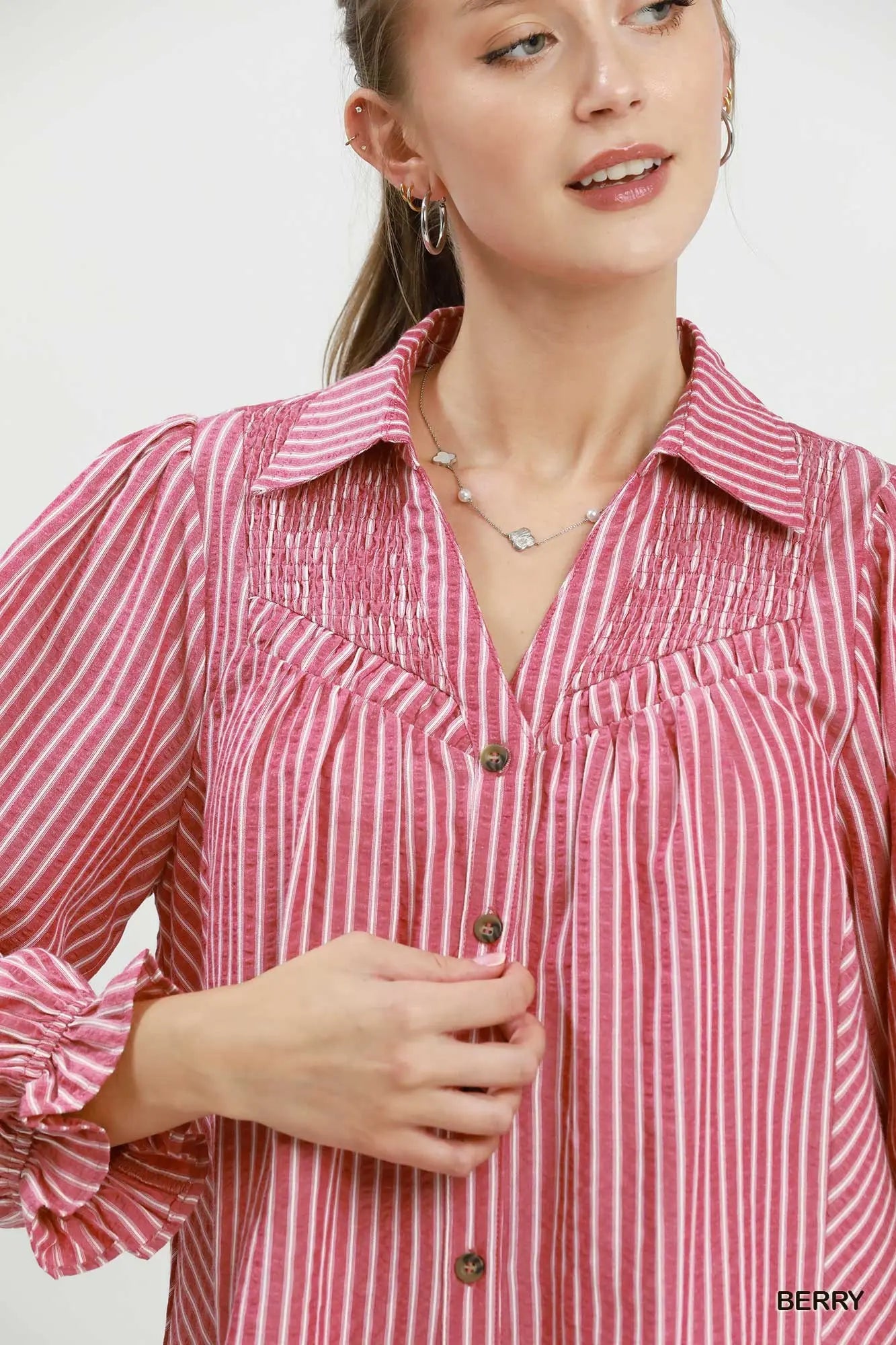 Woman wearing a pink and white striped shirt with a plain background