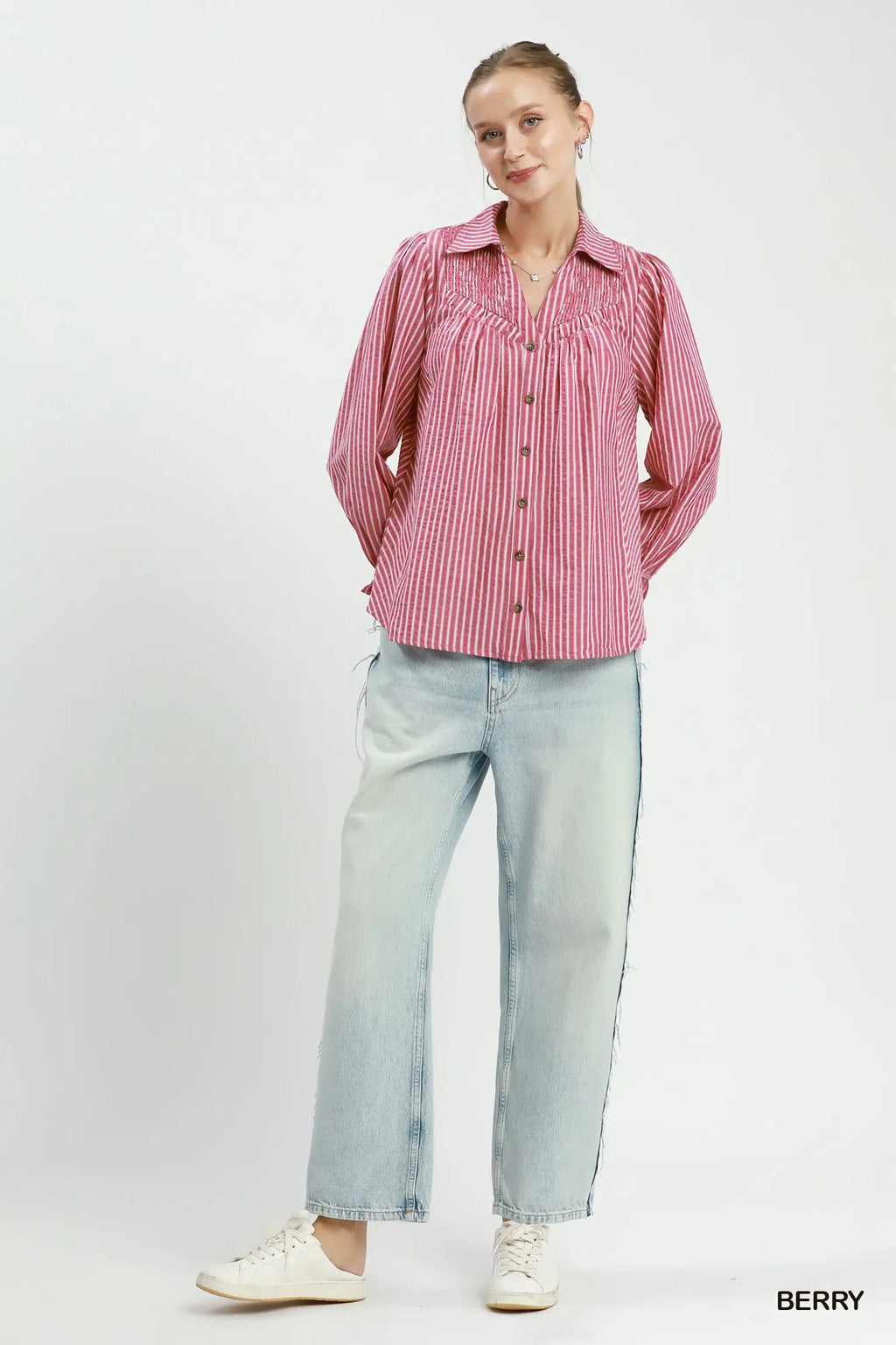 Woman wearing a pink striped shirt and light blue jeans on a white background