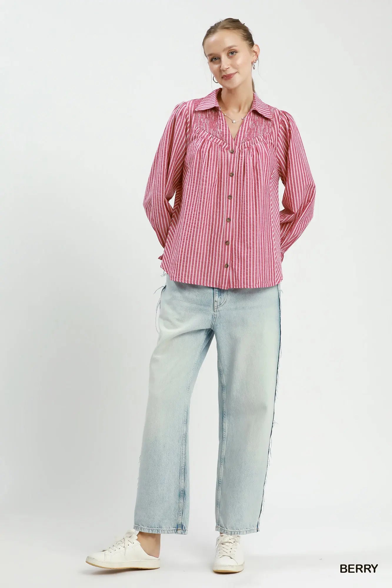 Woman wearing a pink striped shirt and light blue jeans on a white background