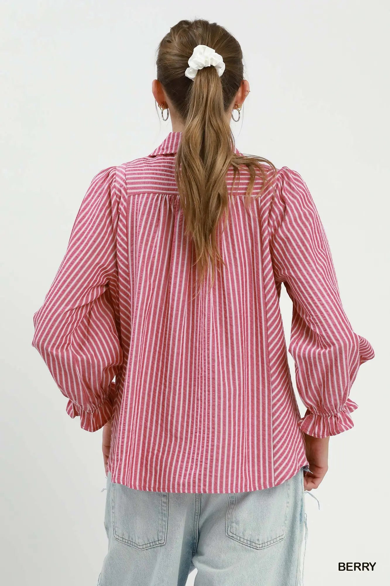Person wearing a red and white striped shirt with puffed sleeves on a plain background