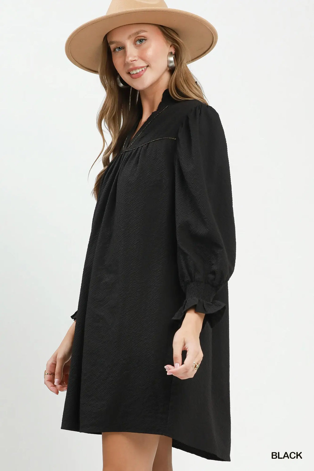 Woman wearing a black dress and beige hat on a white background