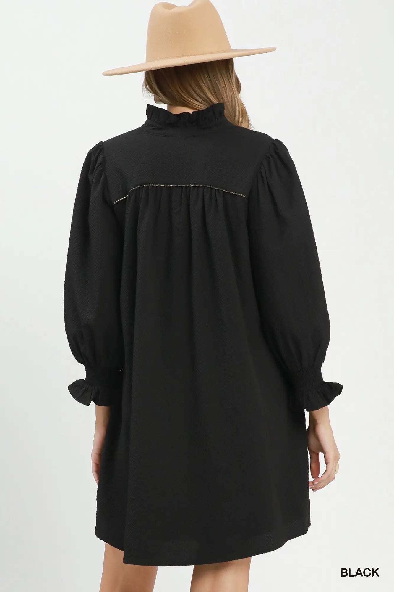 Black dress with long sleeves and a high collar worn by a person on a white background