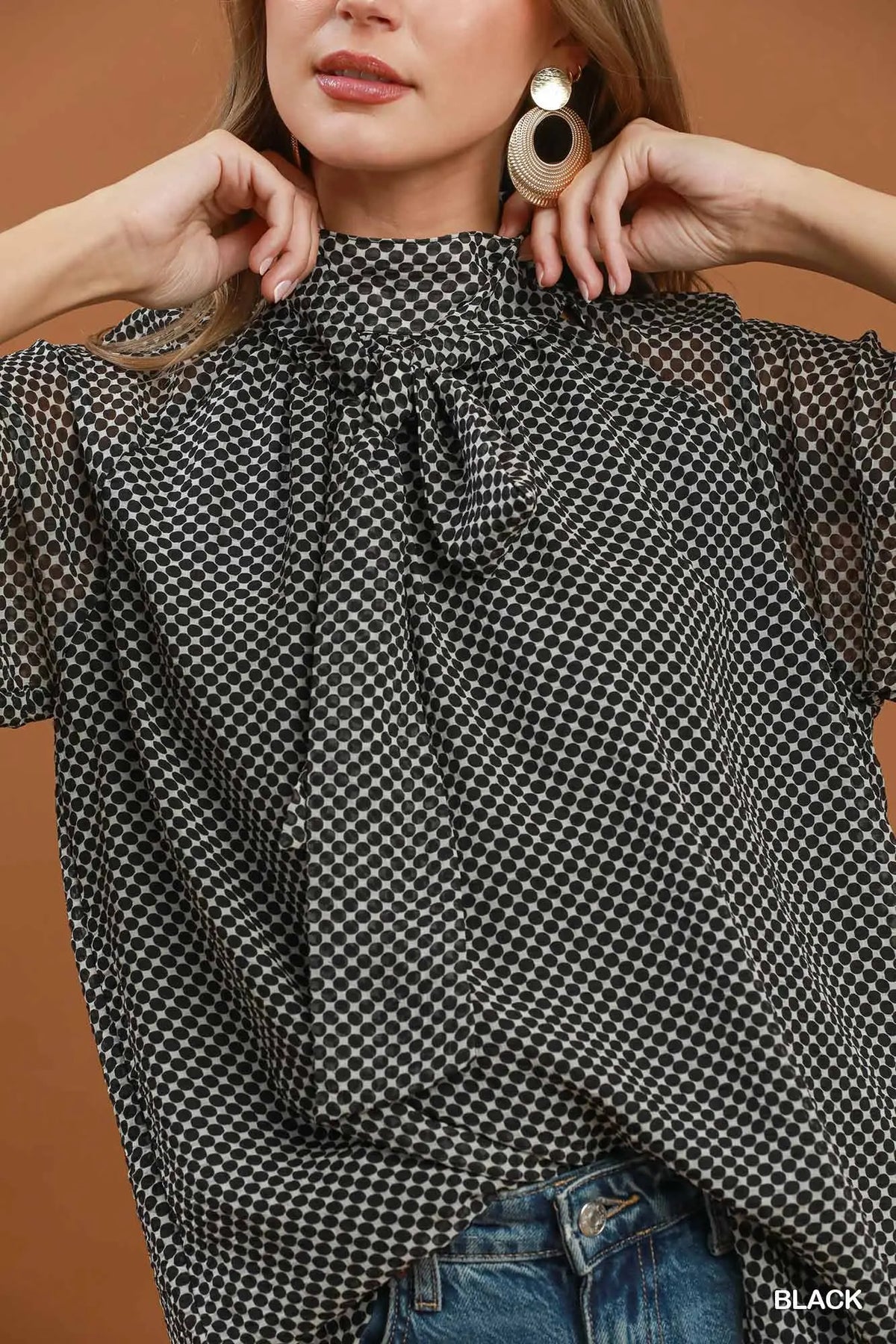 Woman wearing a black and white checkered blouse with a brown background