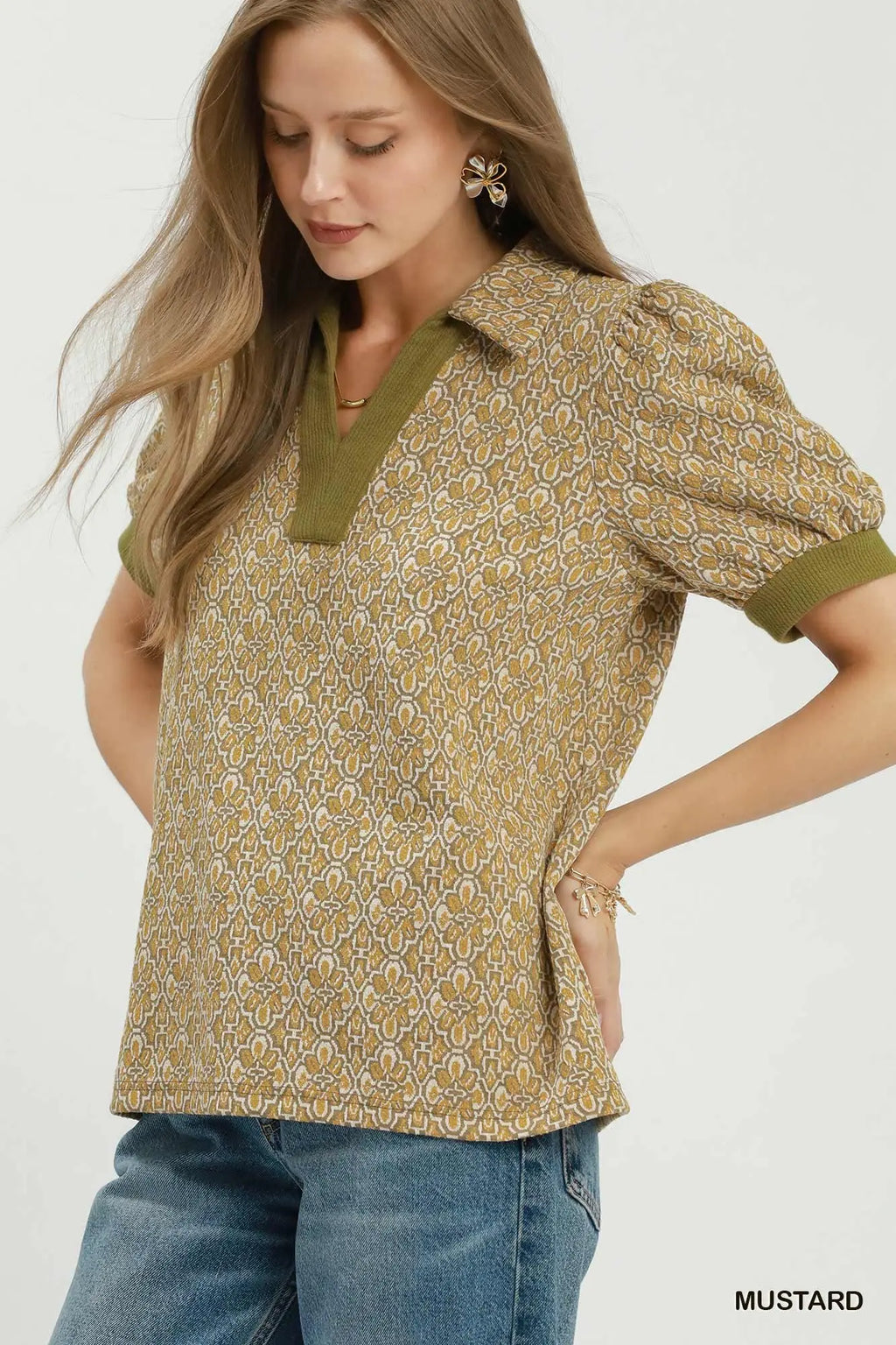 Woman wearing a patterned blouse with green accents on a white background
