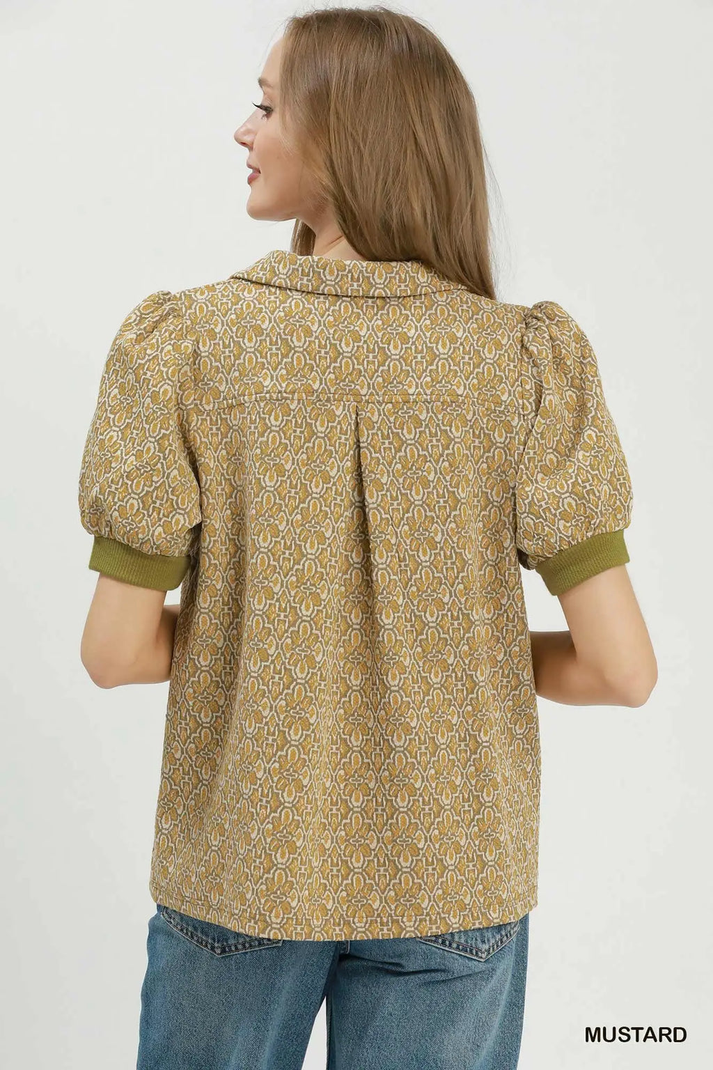 Woman wearing a mustard yellow patterned blouse with puff sleeves on a white background