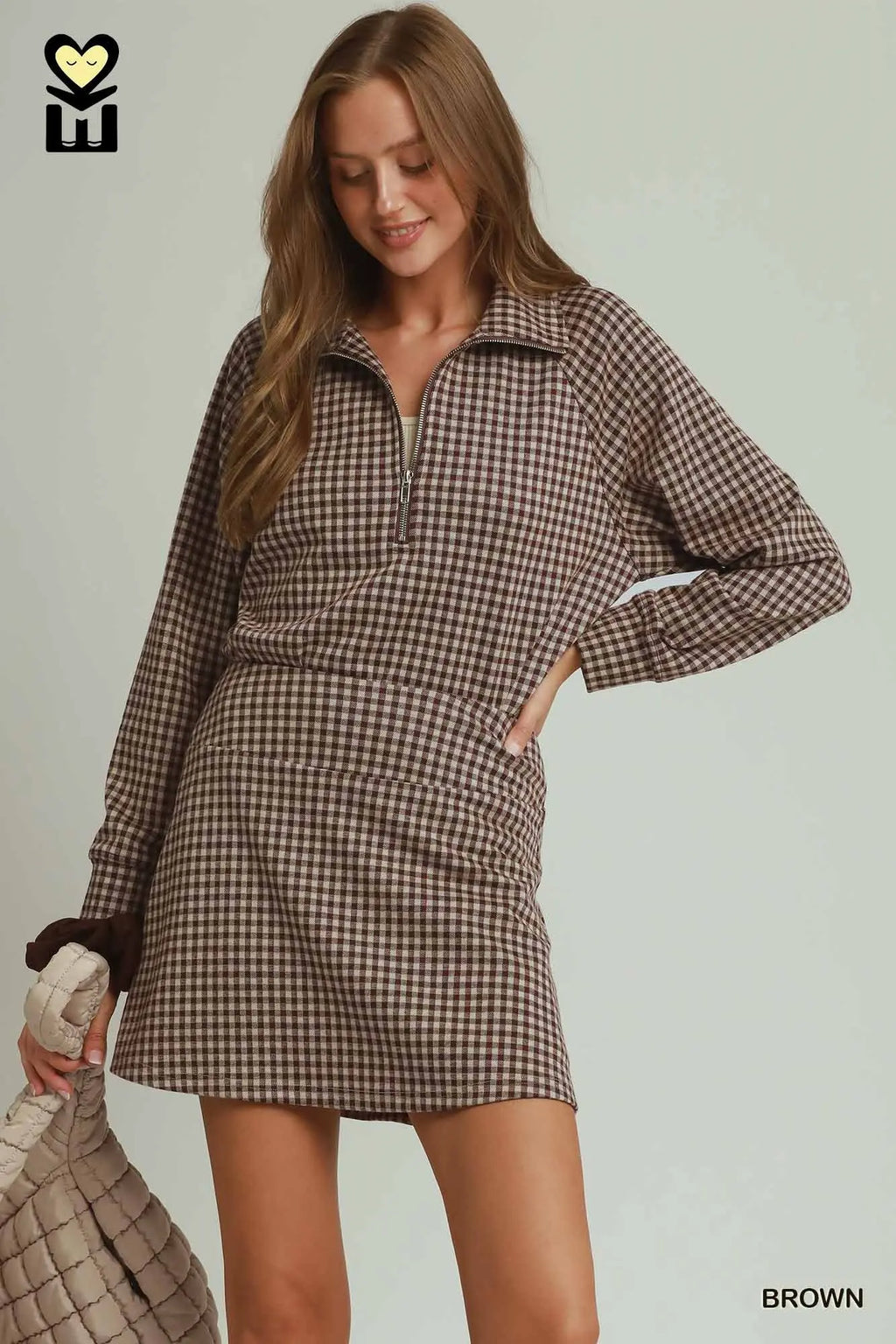 Woman wearing a brown checkered dress with a neutral background