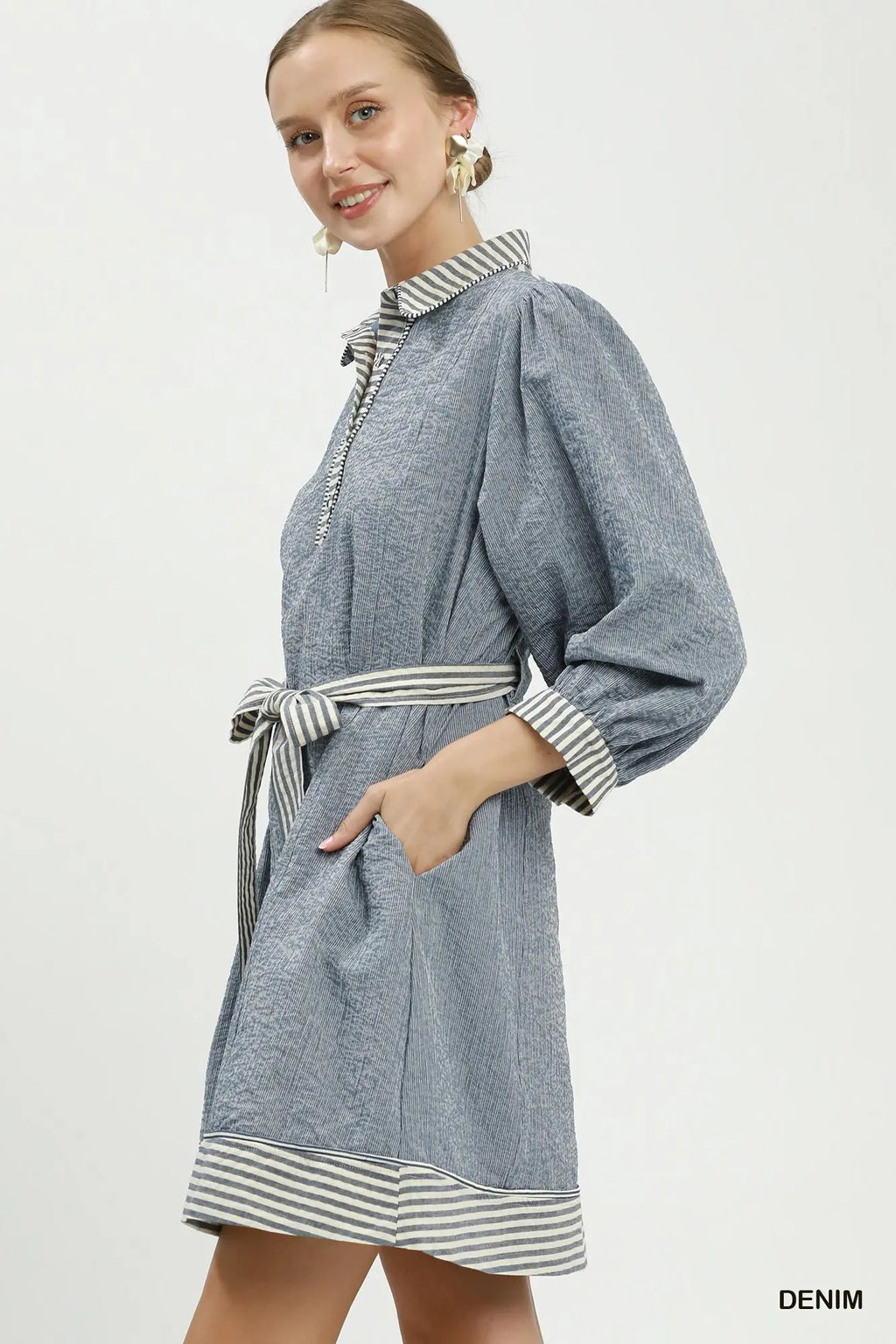Woman wearing a denim dress with striped details on a white background