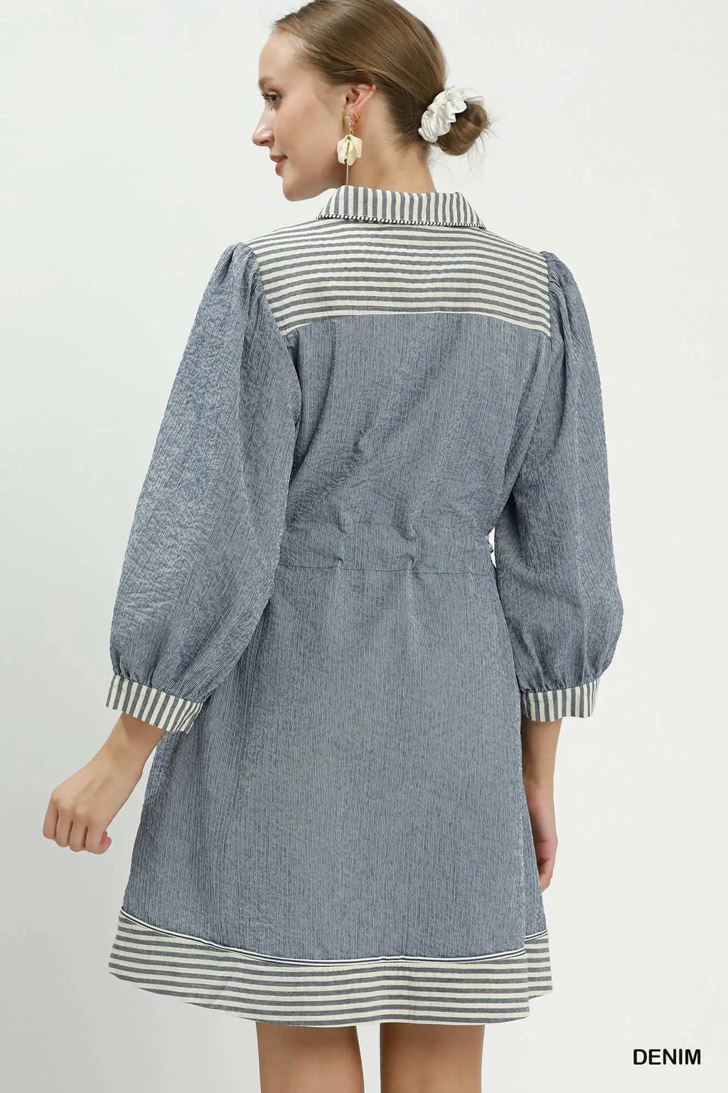 Woman wearing a denim dress with striped details on a white background