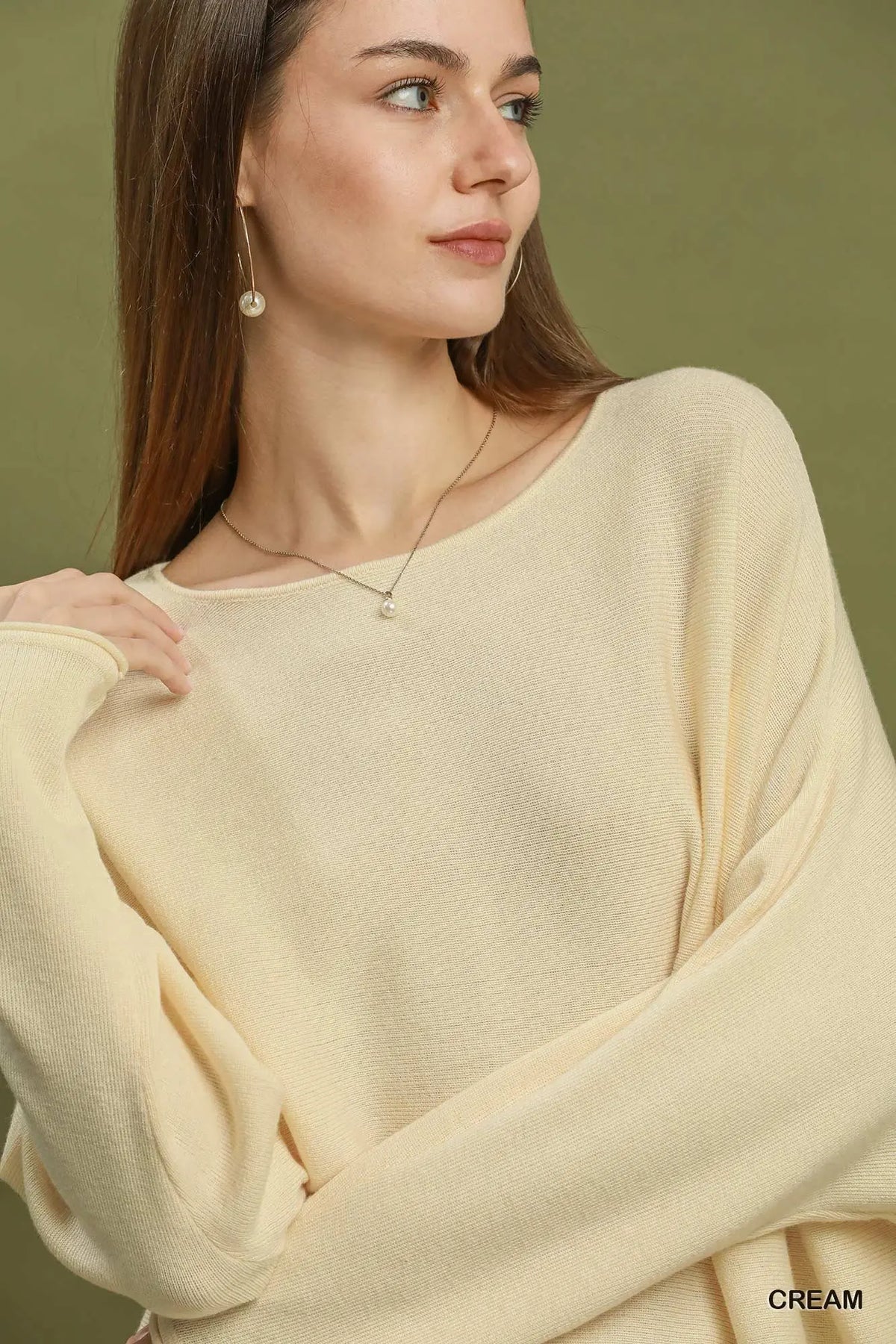 Woman wearing a cream sweater against a green background