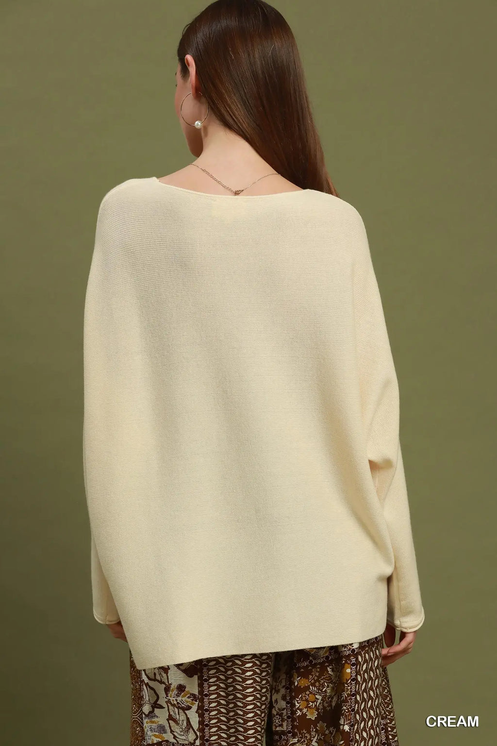 Woman wearing a cream sweater against a green background