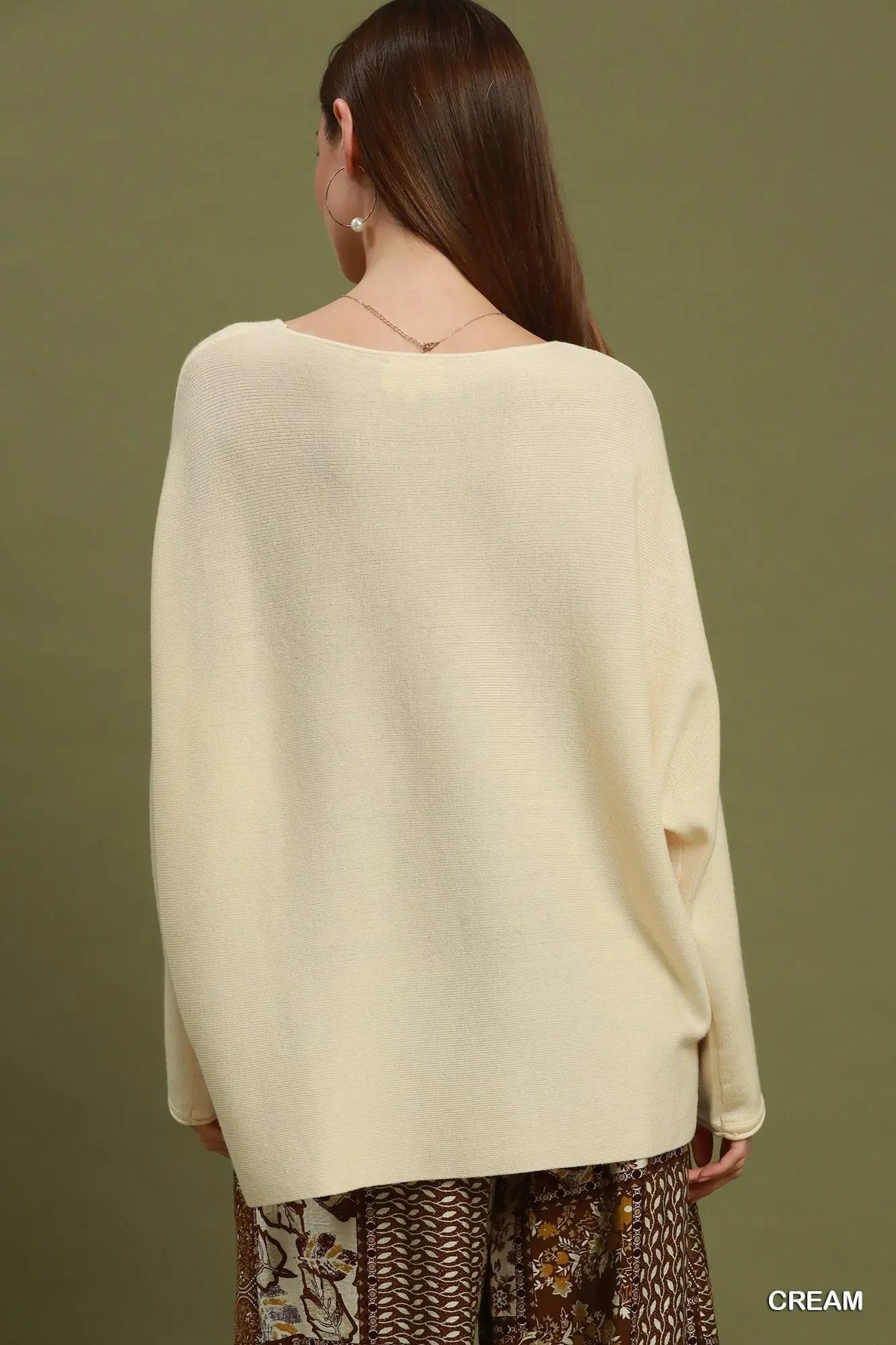 Woman wearing a cream sweater against a green background