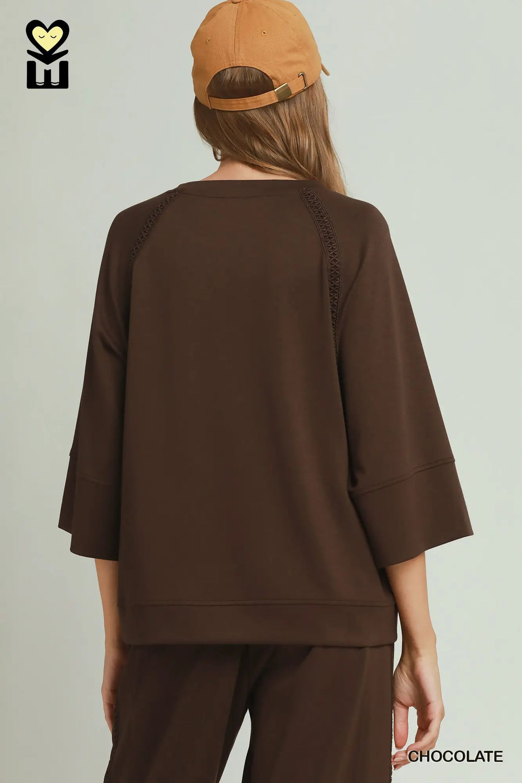 Person wearing a brown outfit with a cap on a light gray background
