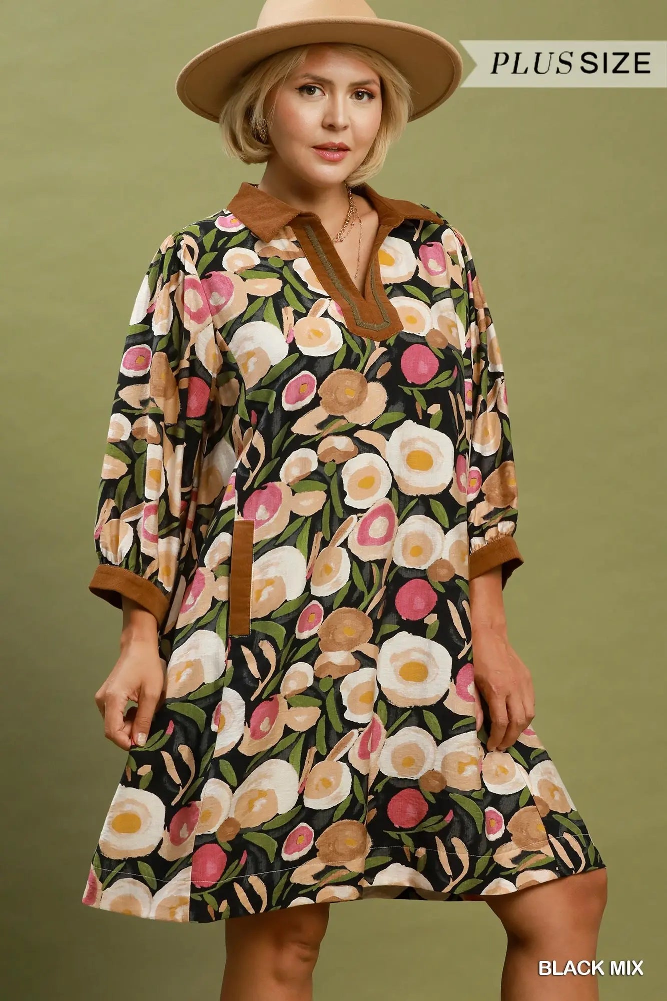 Woman wearing a floral dress with a brown collar and cuffs on a green background