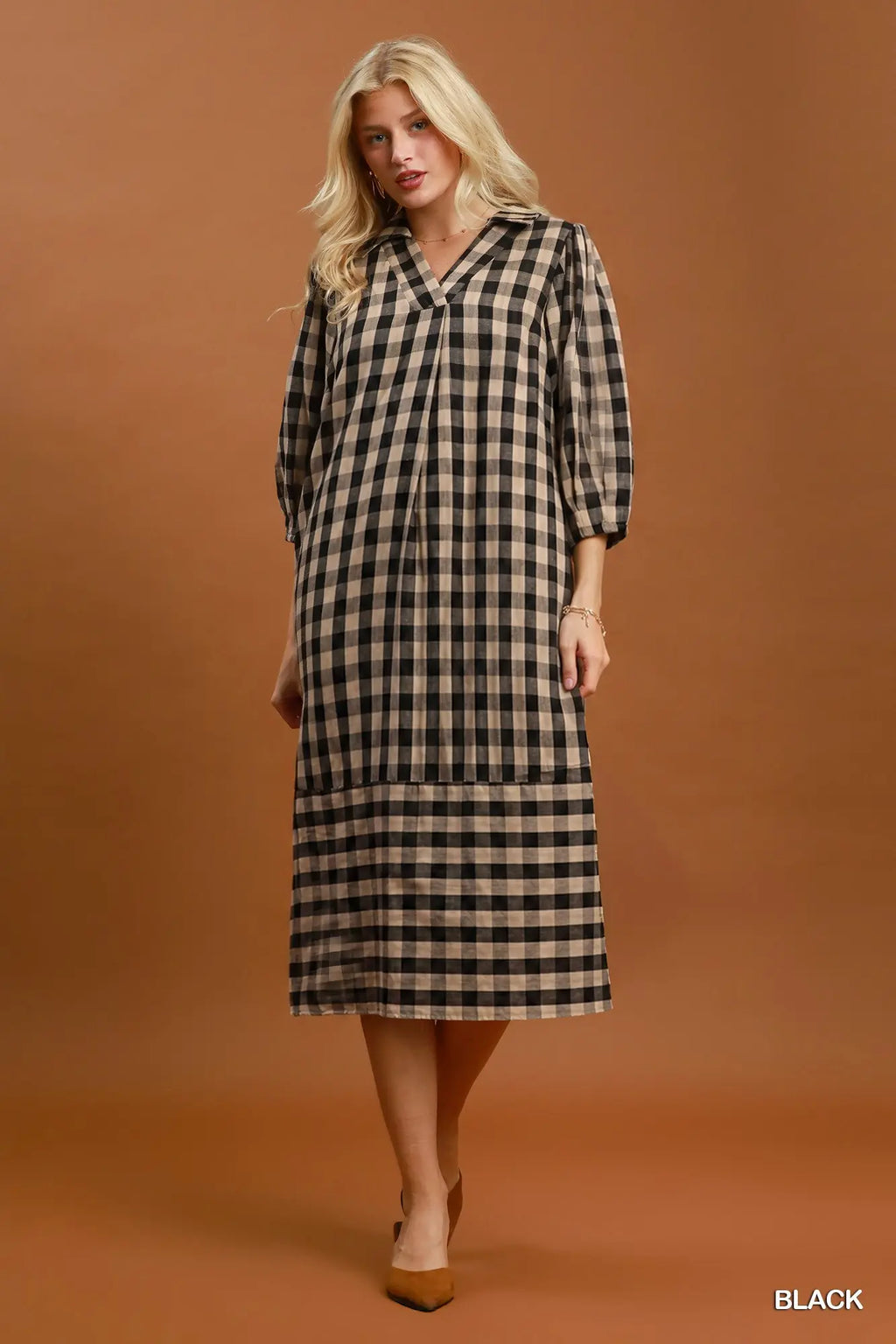 Woman wearing a black and beige checkered dress against a brown background