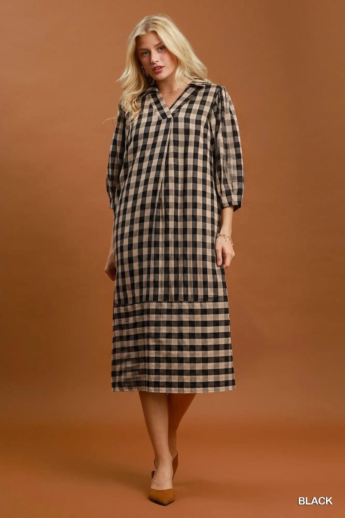 Woman wearing a black and beige checkered dress against a brown background