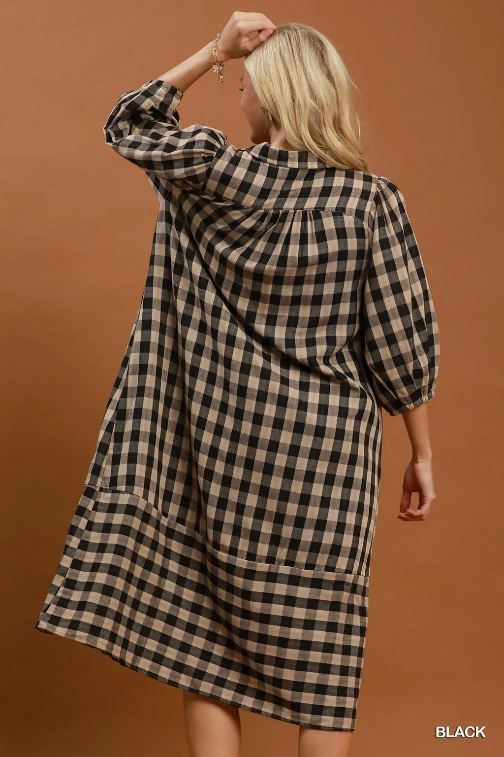 Woman wearing a black and beige checkered dress against a brown background