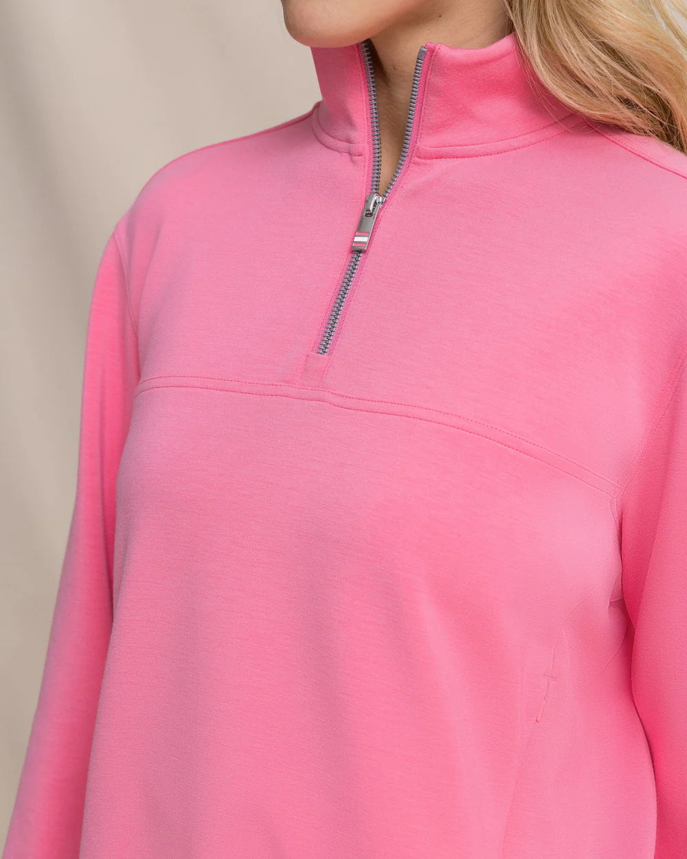 Close-up of a pink pullover with a quarter zip on a neutral background