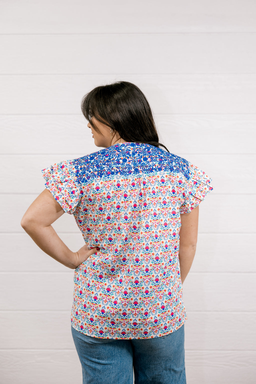 Woman wearing a colorful floral blouse against a white background