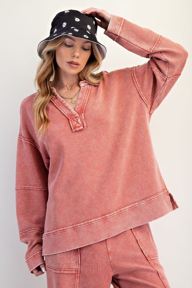 Woman wearing a pink sweatshirt and pants with a black floral bucket hat on a white background