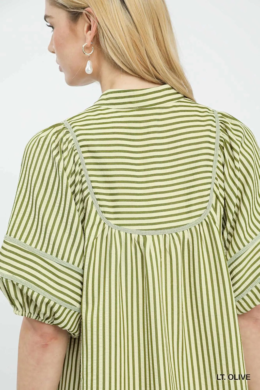 Green and white striped shirt worn by a person on a light gray background