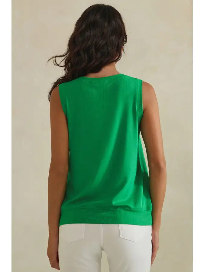 Woman wearing a green sleeveless top against a beige background