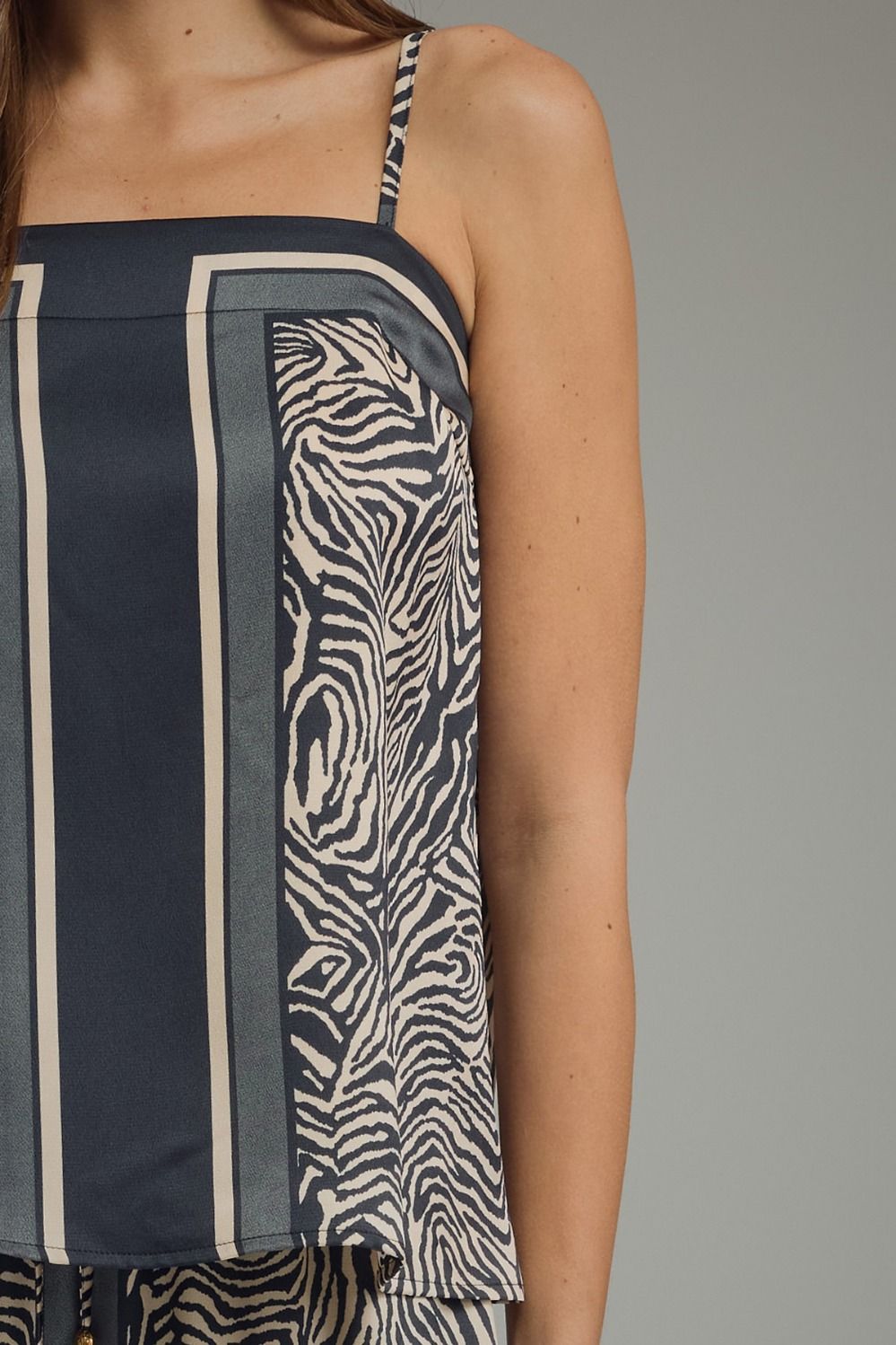 Woman wearing a sleeveless dress with zebra pattern and vertical stripes on a gray background
